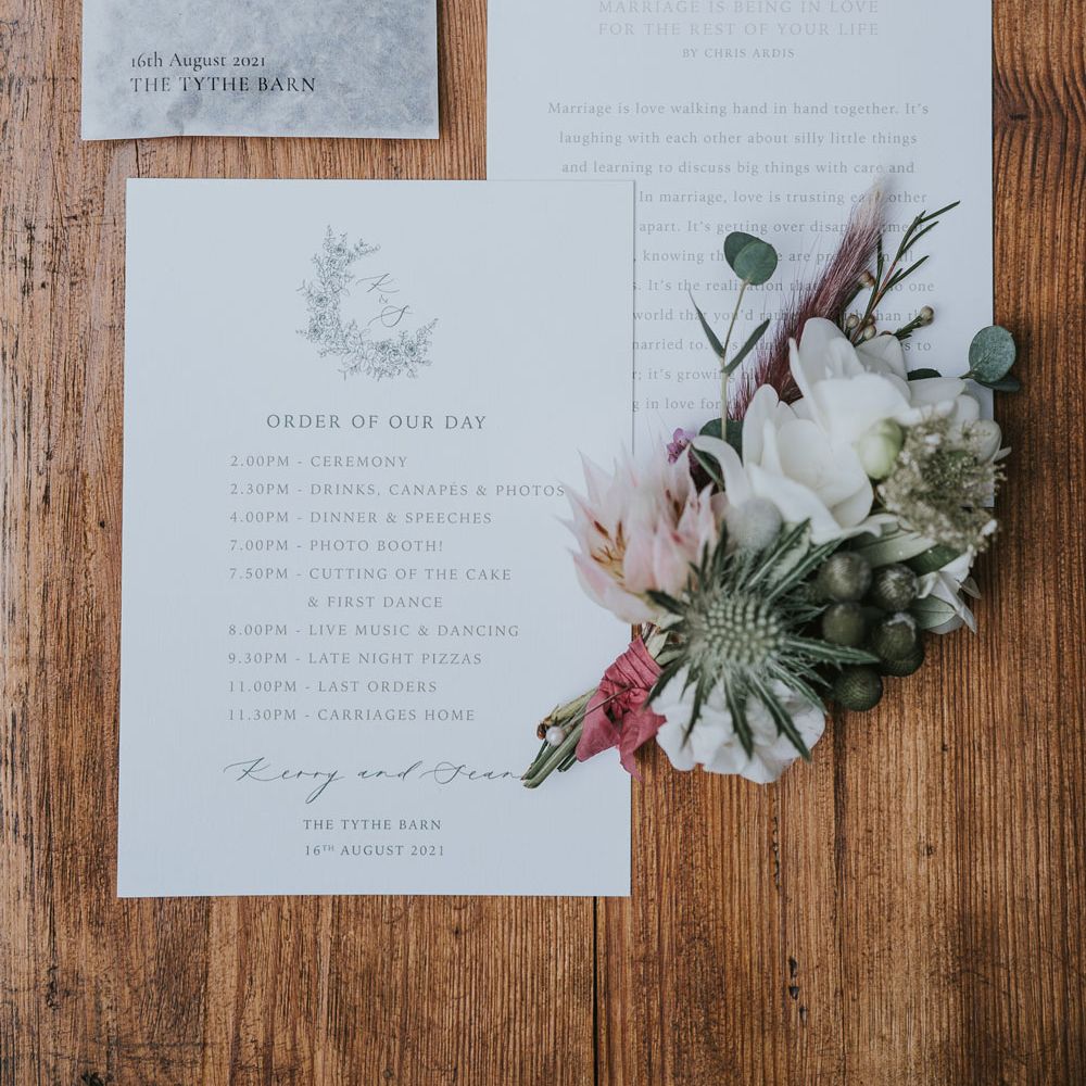 White order of the day and wedding reading, personalised wedding confetti and buttonhole with protea and white flowers at Tythe Barn wedding with barn wedding flowers