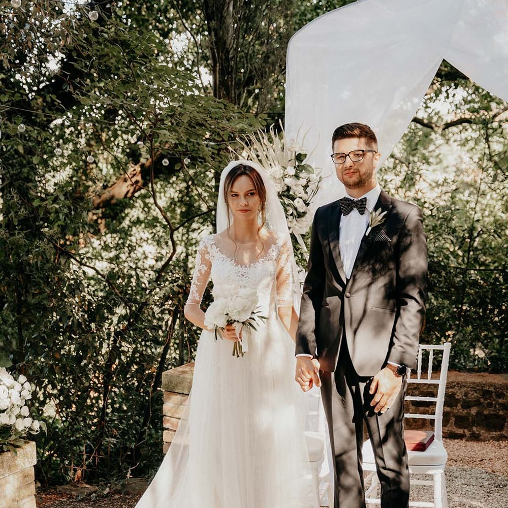 Bride & groom stand together after their wedding ceremony outdoors as groom wears black tie | Royal Studio