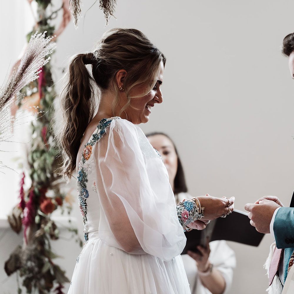 Bride with ponytail and mesh sleeve wedding dress exchanges rings with groom in red kippah and tallit during wedding ceremony at Iscoyd Park