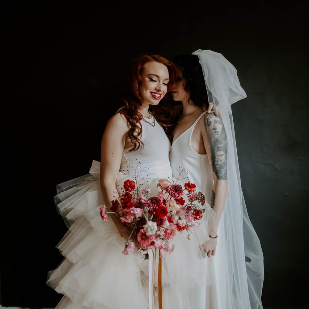 Two brides in a high low tulle skirt wedding dress and satin slip with long bow veil at Manchester elopement 