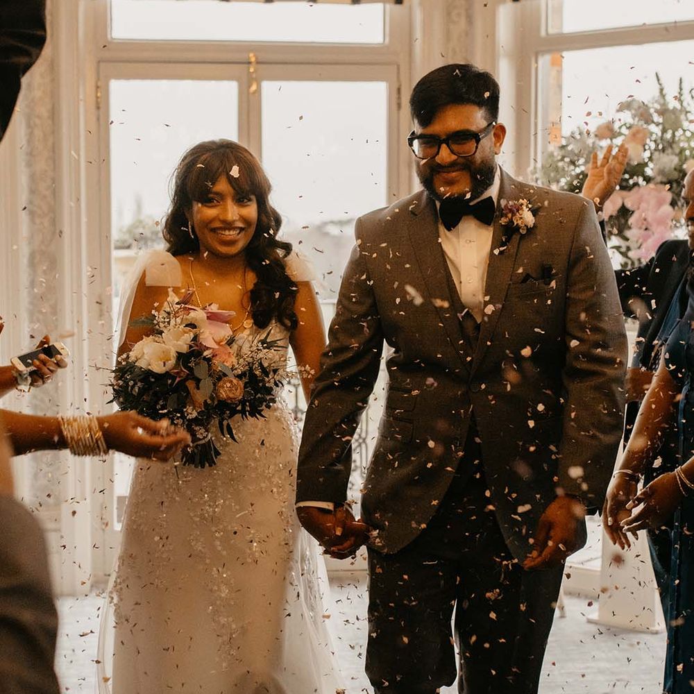 Bride in traditional white wedding dress with mixed flowers bouquet and groom in dark grey suit with black bowtie 