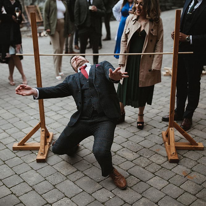 Man does the limbo for outdoor wedding games 