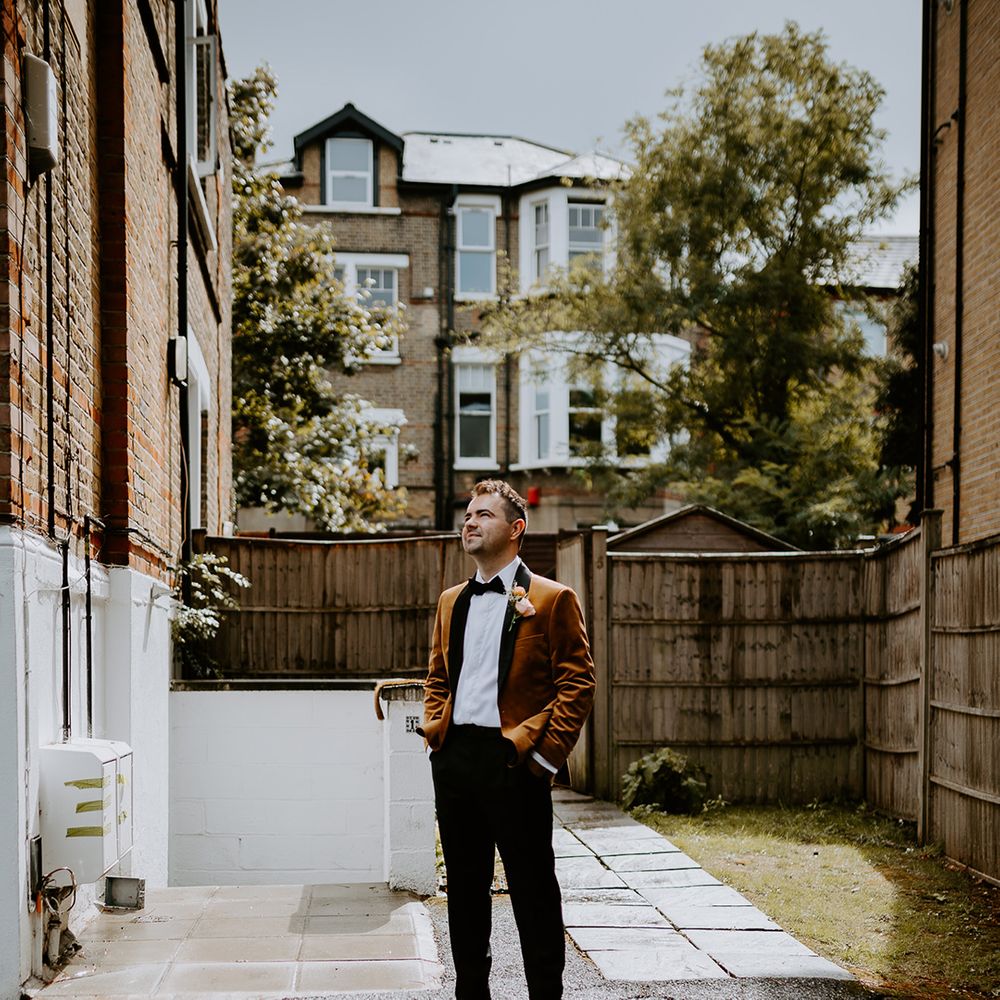 Groom shows off alternative wedding suit featuring a burnt orange velvet blazer