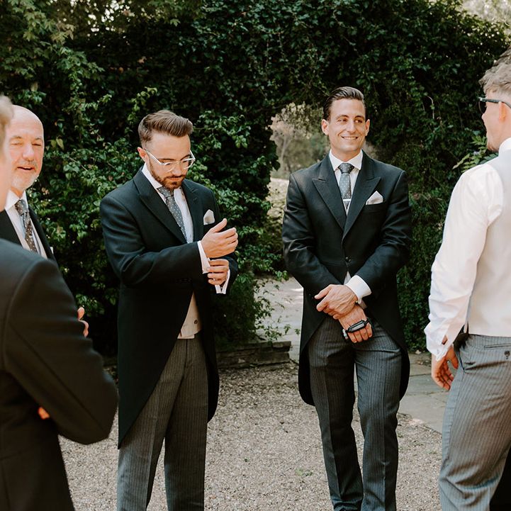 Groom stands outside with the groomsmen as they all get ready together in the morning for the day 