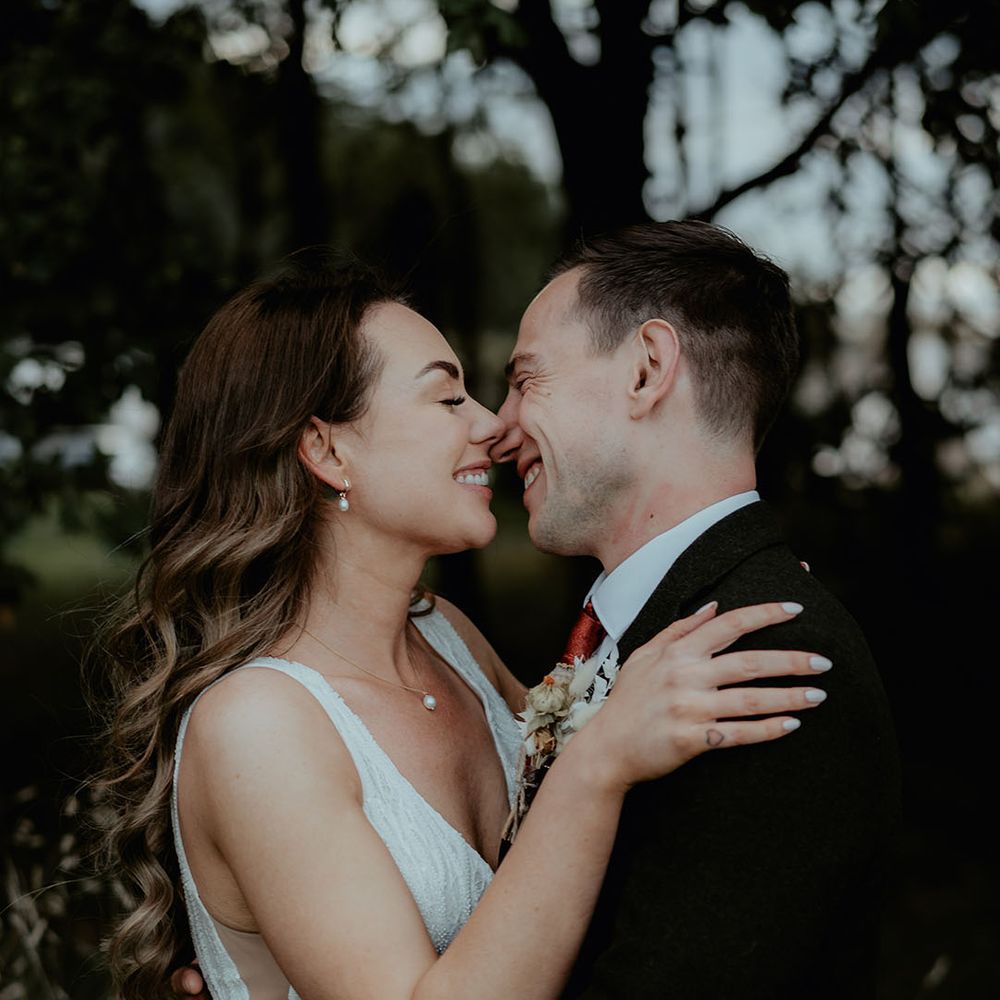 The bride and groom lean in for a kiss as they pose for couple portraits on their wedding day 