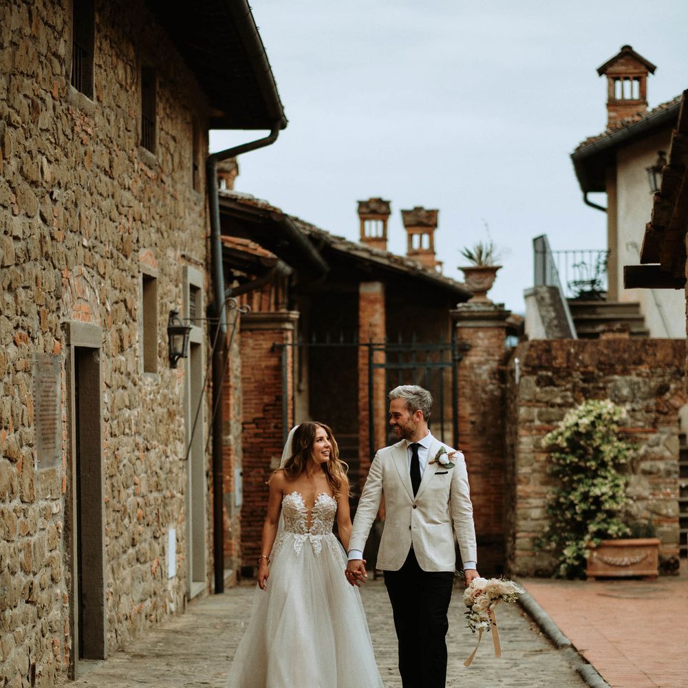 Bride in white embroidered tulle wedding dress with groom in linen suit walking through Italian villa at destination wedding