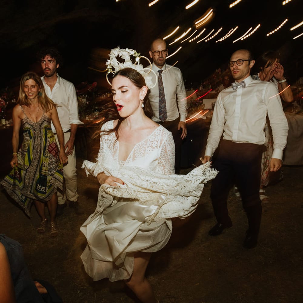 Bride in lace wedding dress, pearl earrings and bridal crown dances at wedding reception in Italy
