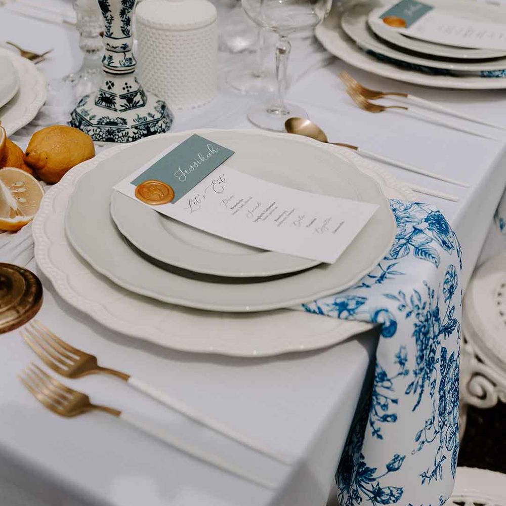 place setting with blue and white napkin and candlestick holders, intricate tableware, white cutlery and lemon decor