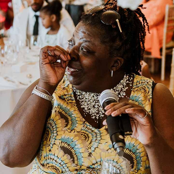 Wedding guest in yellow blue and brown dress doing wedding speech and tearing up at Tredudwell Manor 