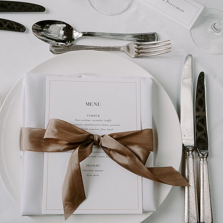 White classic wedding place setting with wedding menu decorated with brown satin bow decoration 