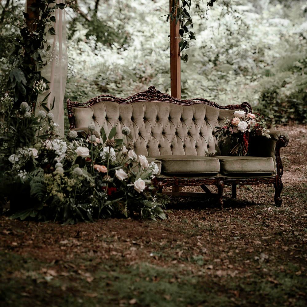 Vintage couch in the woods with locally sourced flowers