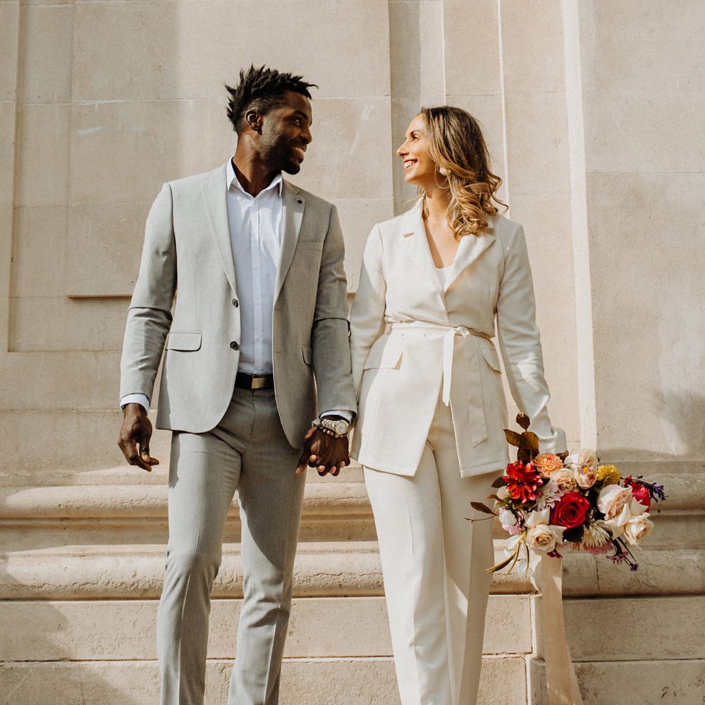 Stylish bride and groom in grey and ivory suits with colourful fashion and footwear