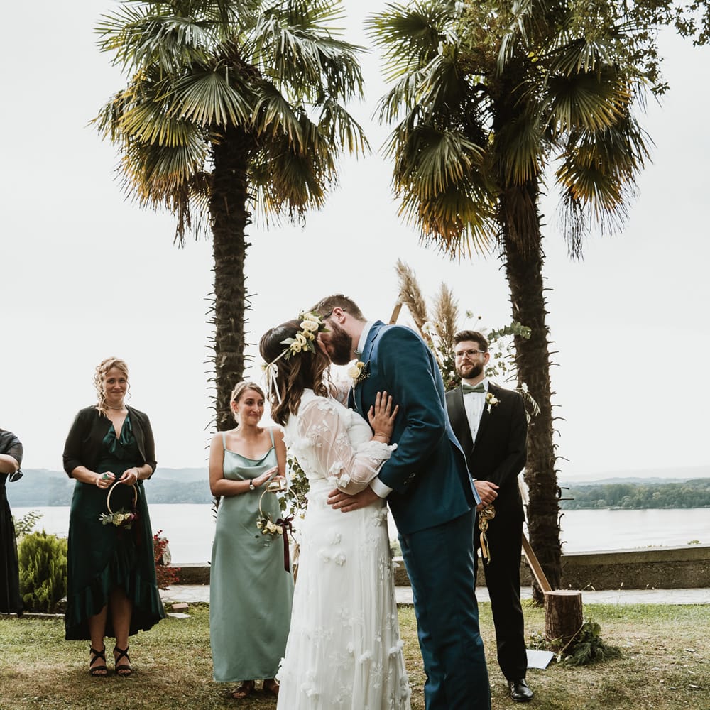 Bride and groom kissing at outdoor wedding ceremony in Italy with bride in a white wedding dress with flowers 
