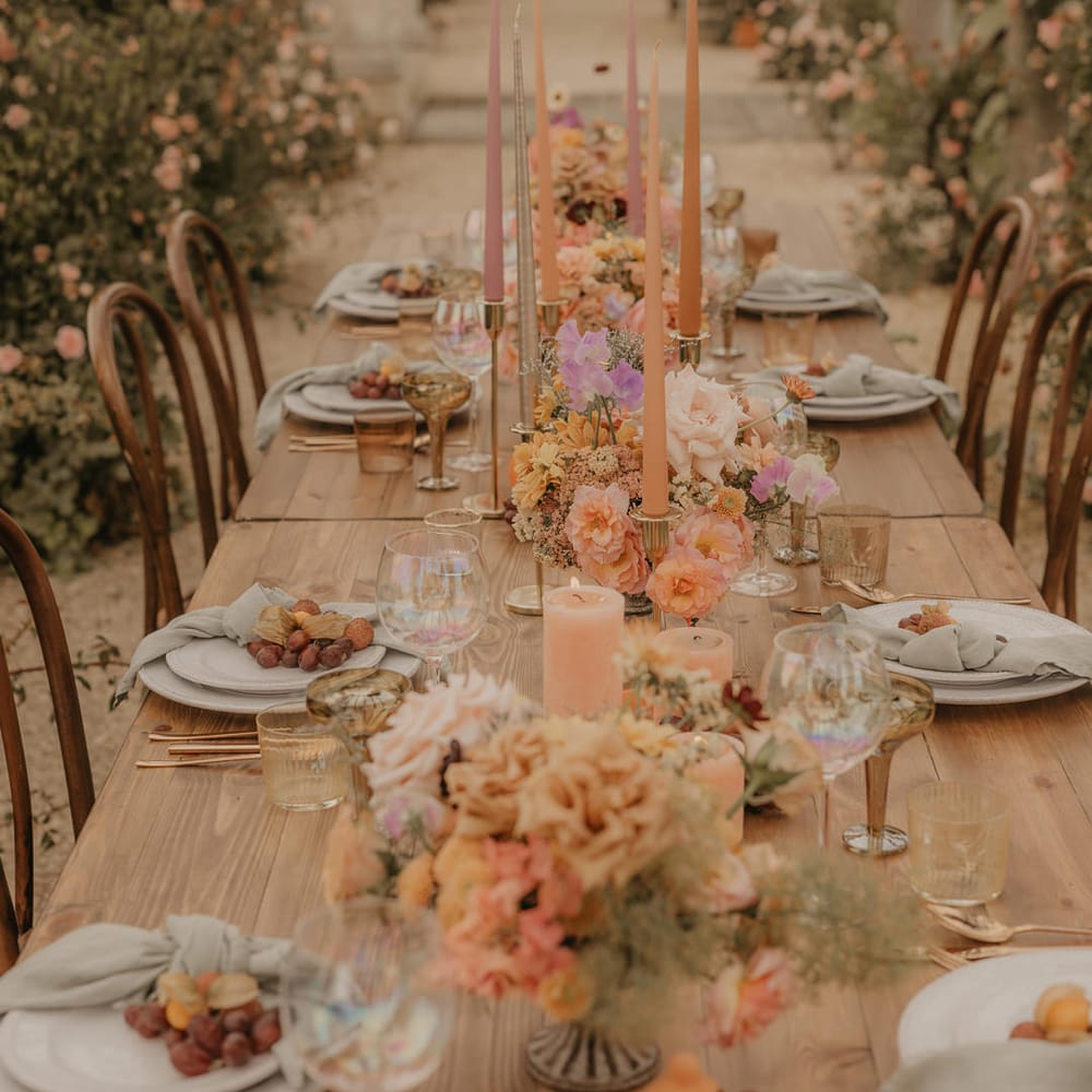 Wedding table decor with flowers, fruits and candles in pastel orange, peach, coral and pink colours 