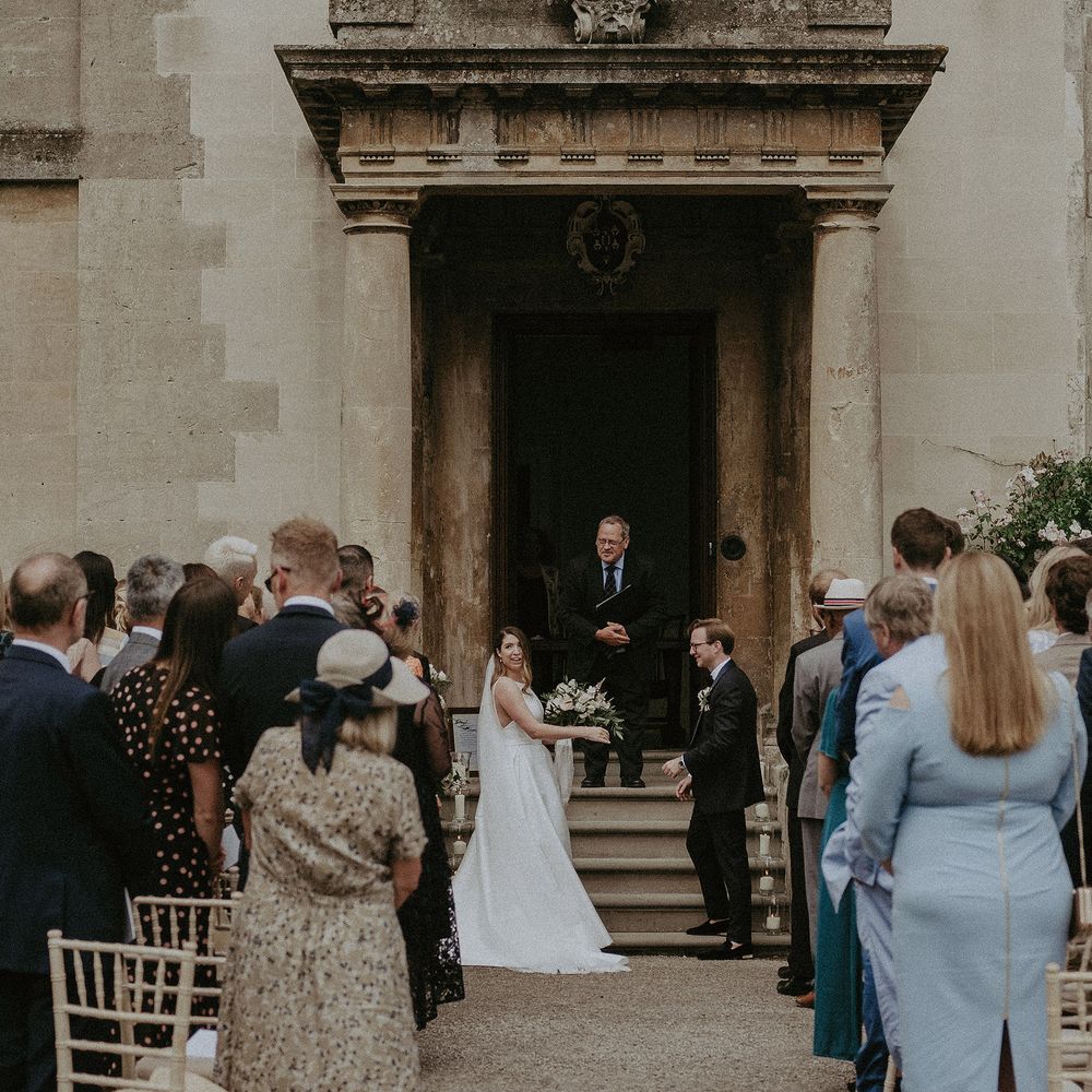 Bride & groom stand in large doorway for outdoor ceremony at Elmore Court 