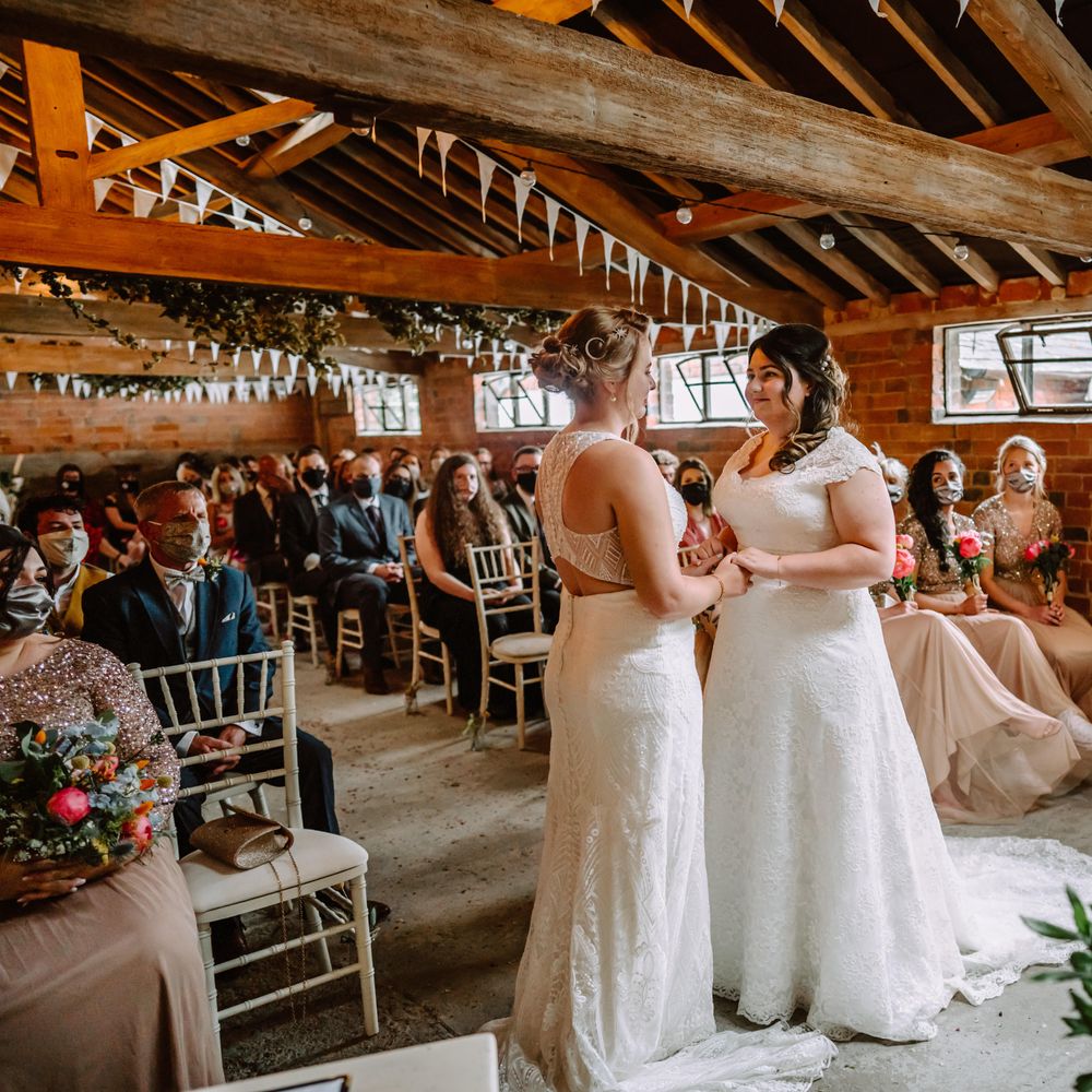 Brides stand together at the front of the aisle during wedding ceremony