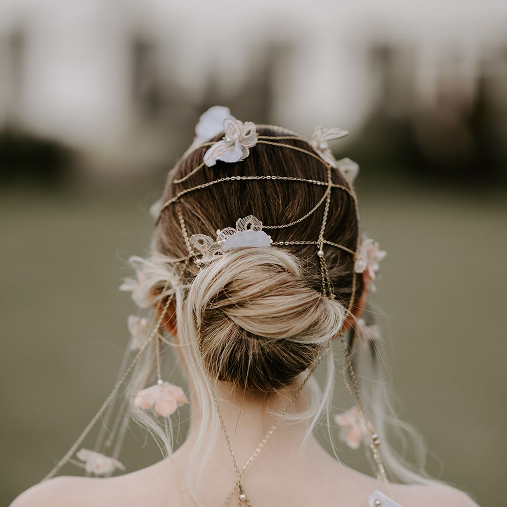 Bride with a bun wedding hairstyle decorated with a chain headdress and back necklace 