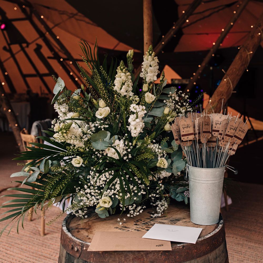 Personalised wedding sparklers next to white and green florals for festival style tipi wedding