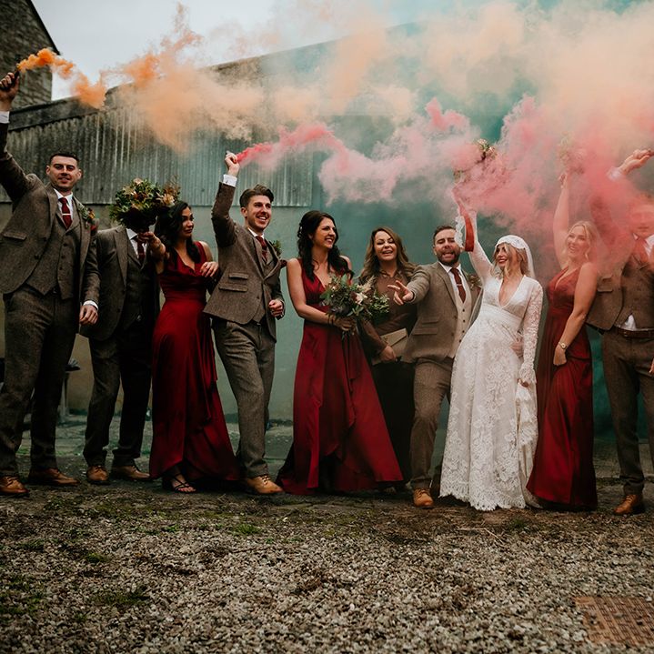 Smoke bomb wedding party portrait at Lyde Court with bride in a lace wedding dress, groomsmen in tweed suits and bridesmaids in satin dresses 