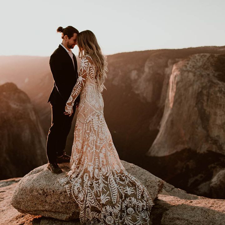 Bride & groom stand on mountain as the sun sets on their wedding day