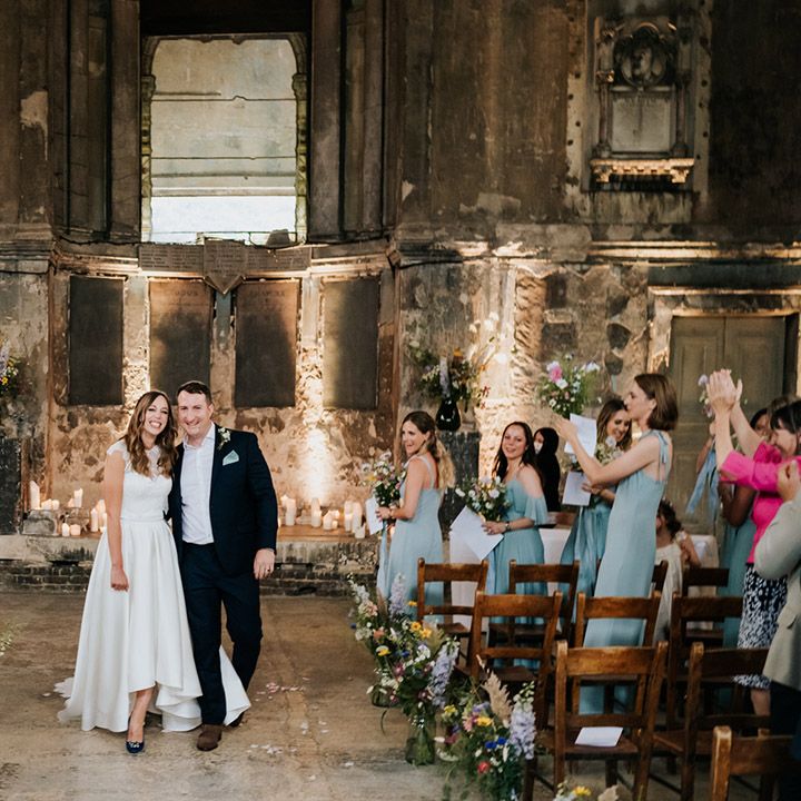 Guests applaud as bride and groom walk back down the aisle together as a married couple