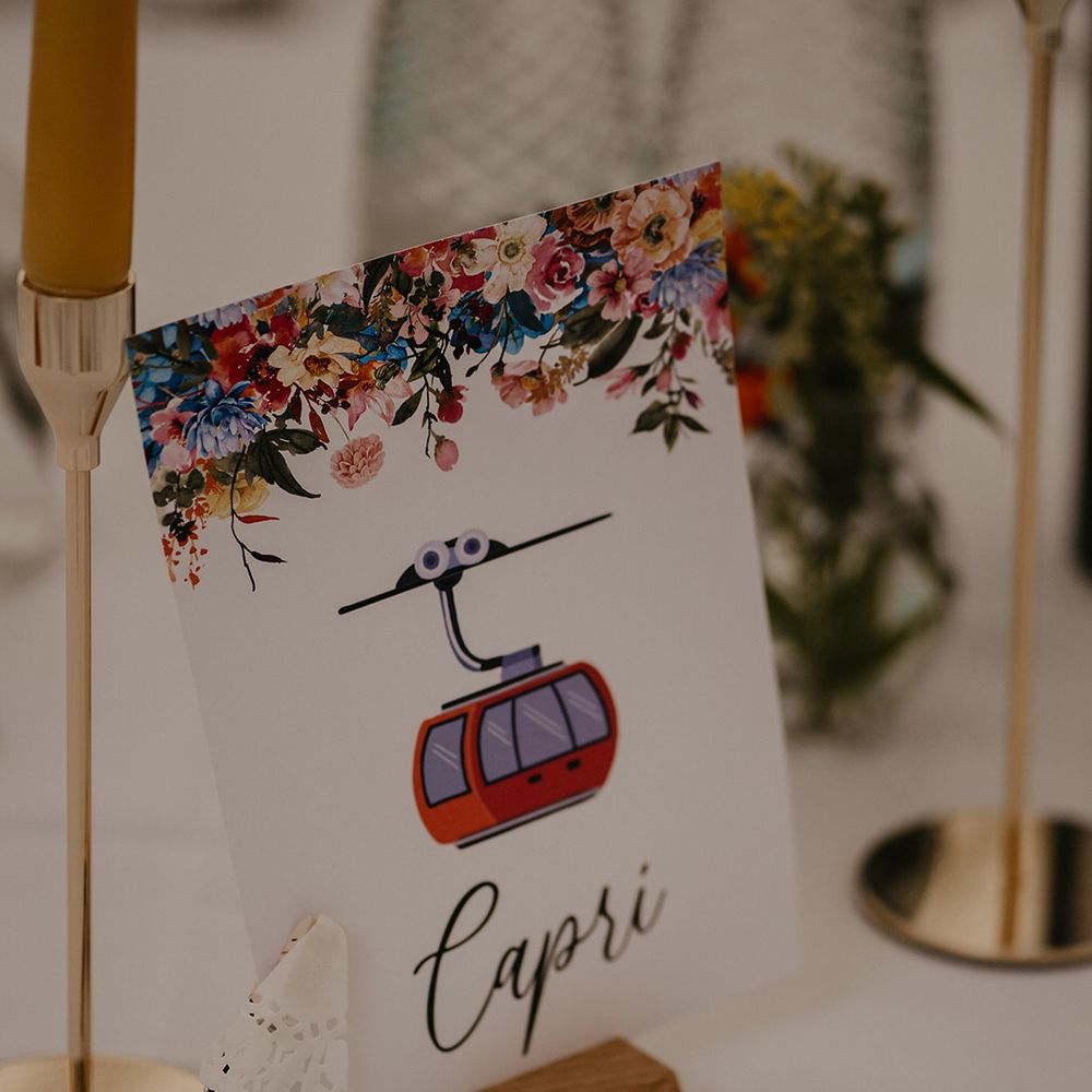Table name place card with floral design and cute cartoon drawing relating to the table name for the couple
