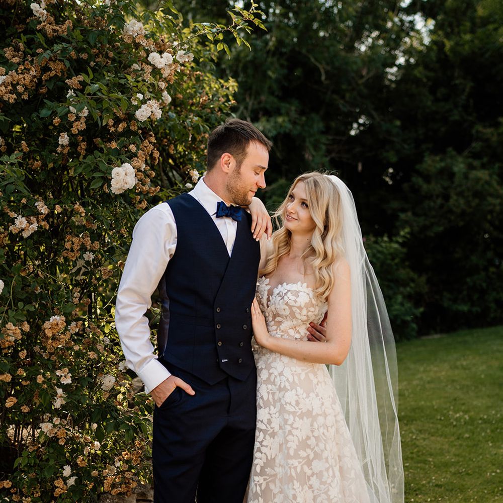 Bride in strapless wedding dress with veil with groom in dark blue waistcoat and bow tie