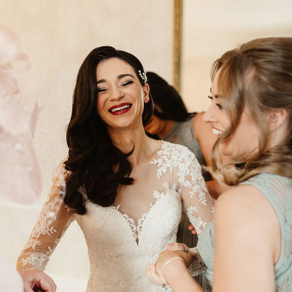 Bride wears lace wedding gown complete with red lipstick and dark hair in loose curls 