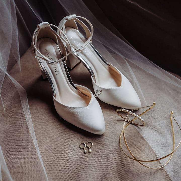 Rainbow Club white wedding shoes with gold headband, pearl earrings, diamond engagement ring, and pearl bracelet 