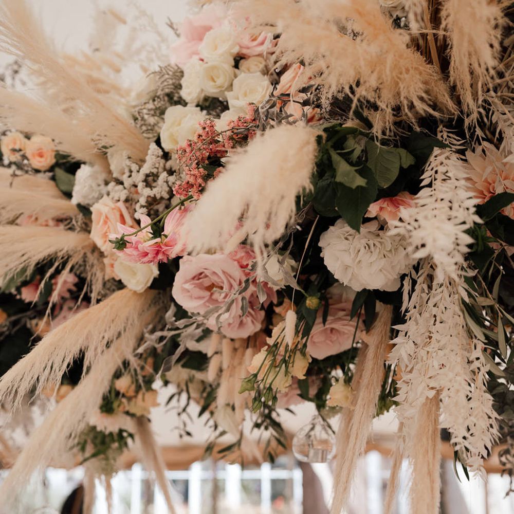 Pink and white wedding flower installation with pampas grass decor and hanging candles 