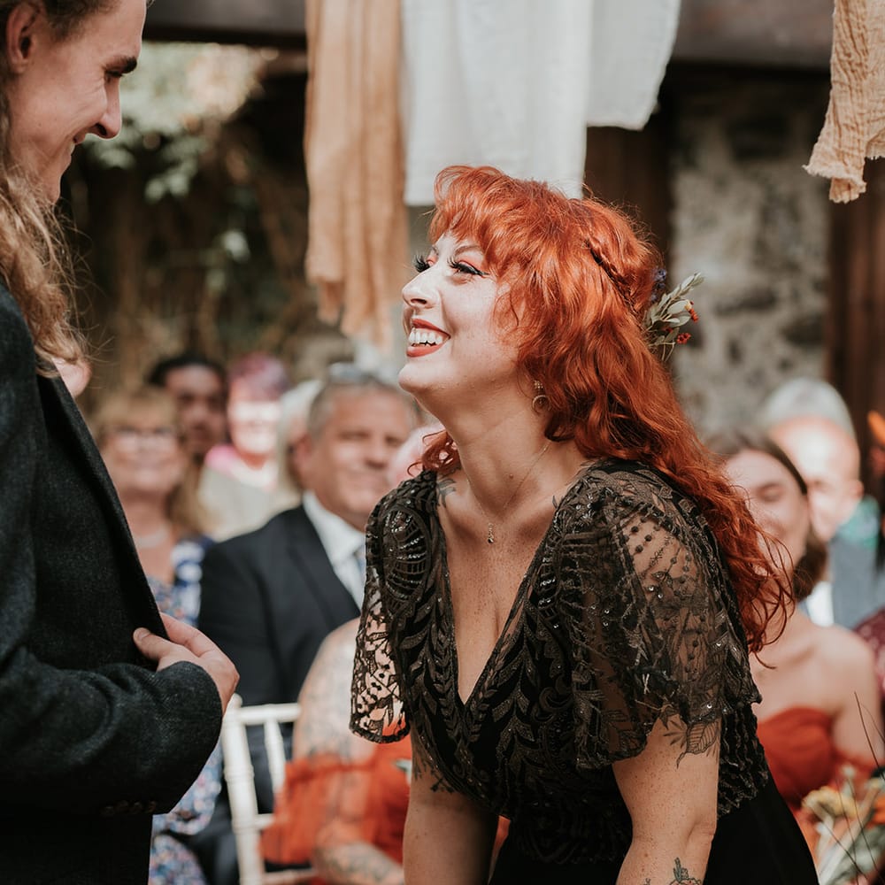 Bride in embellished v neck black wedding dress laughing and smiling at Devon wedding venue 