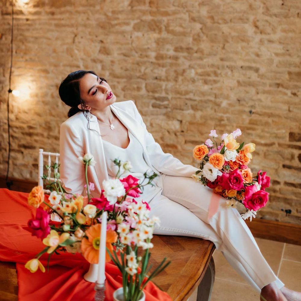 Bride in white bridal suit with closed toe bright green wedding heels holding large mixed flower seasonal bridal bouquet at Merriscourt wedding venue 