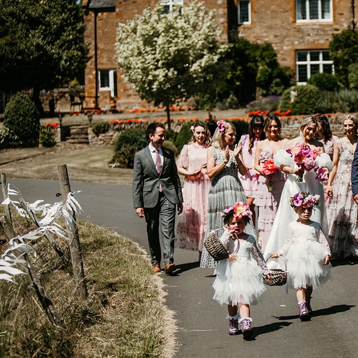 Bridal party with bridesmaids in mismatched dresses, the flower girls in tulle white dresses and flower crowns with father of the bride 