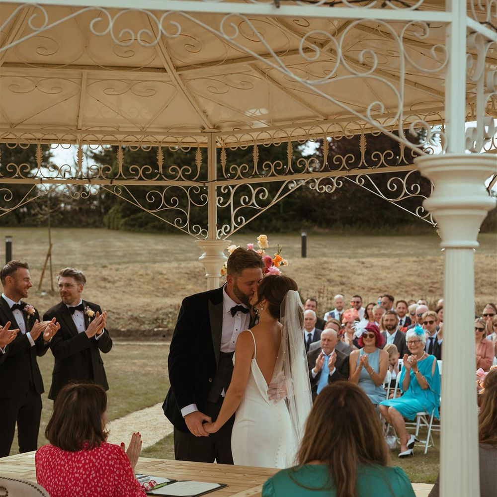 The bride and grooms share their first kiss as a married couple at their outdoor ceremony at The Pear Tree Purton 