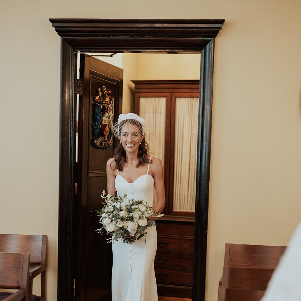 Bride in a separates and wedding headband walking in to her intimate town hall wedding ceremony 