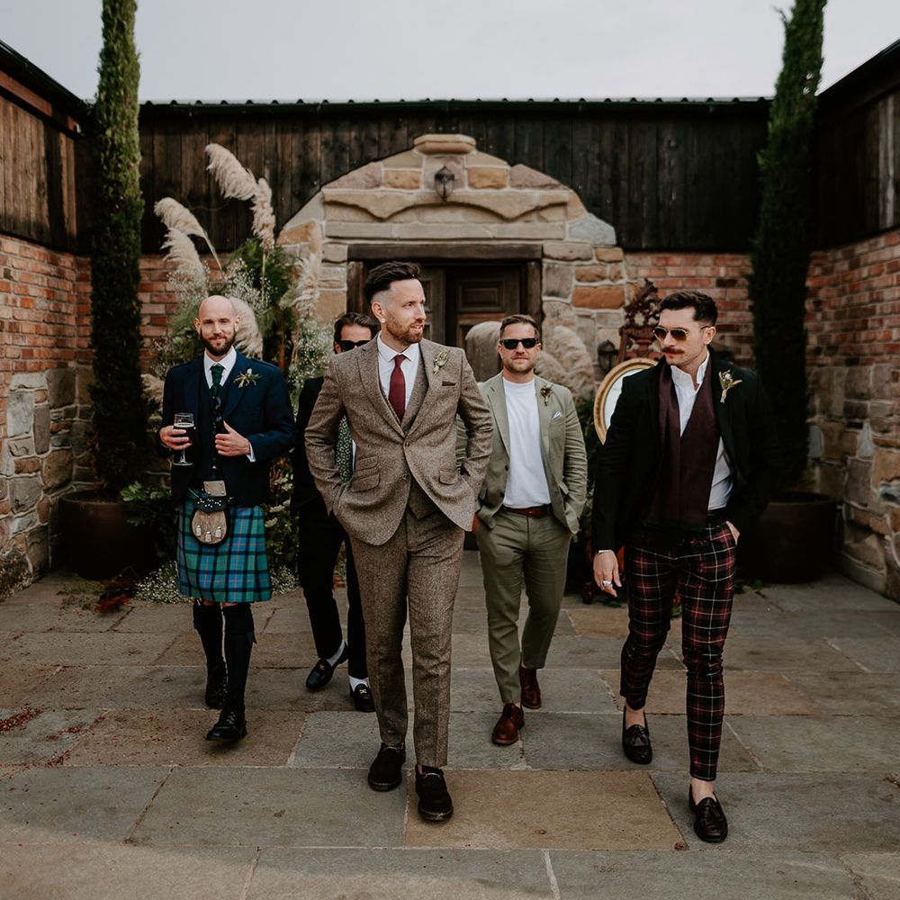 Groomsmen in tartan wedding trousers and kilt with the groom in a grey tweed suit 