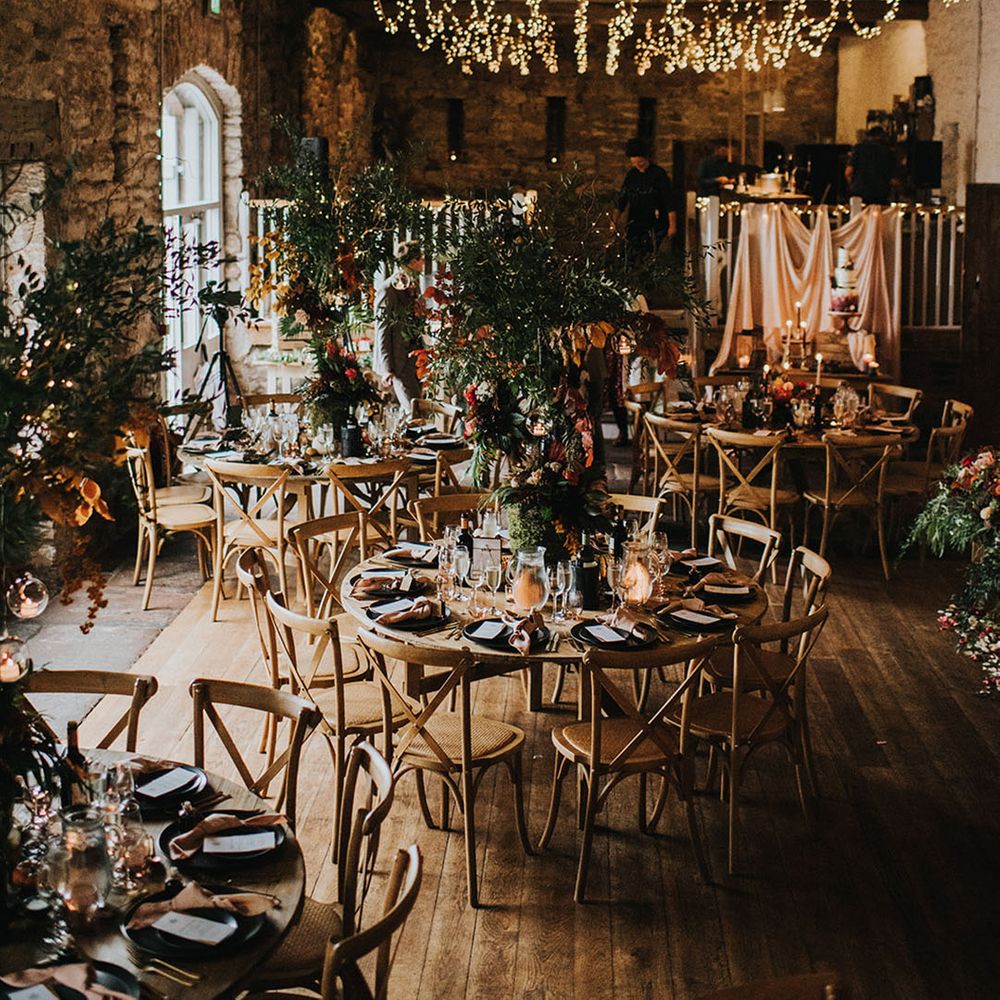 Cosy and gloriously rustic wedding venue with fairy lights and incredible tall centrepieces 