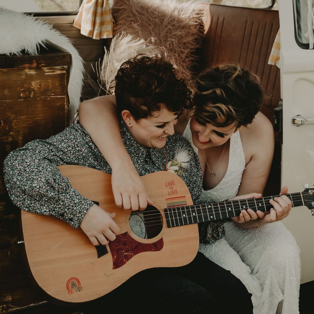 Bride and bride playing guitar in a camper van 