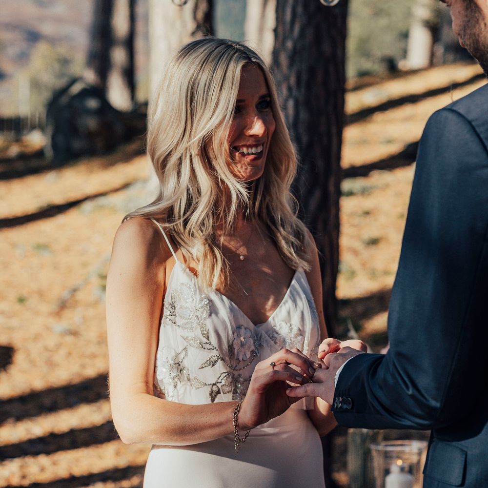 Bride places ring on groom during wedding ceremony
