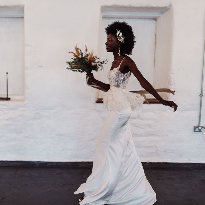 Bride in a fitted wedding dress with thin straps and lace bodice with peplum detail 