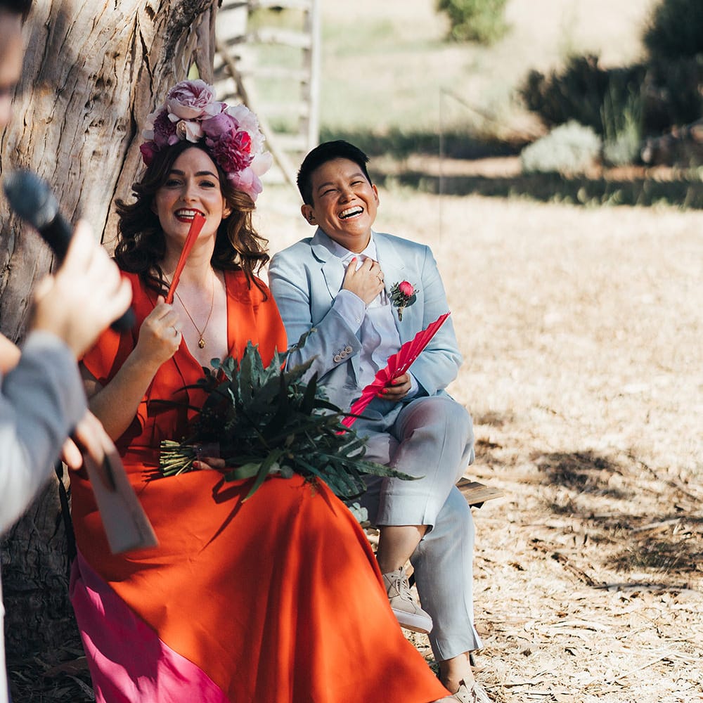 Brides listen during wedding ceremony as they sit together