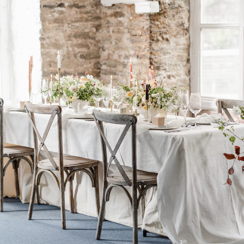 Elegant reception table with wooden chairs, coloured candles and floral centrepiece 
