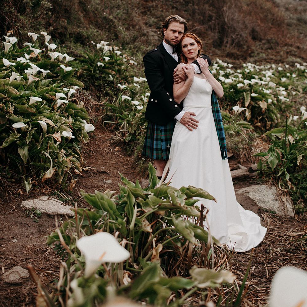 Scottish wedding inspiration with groom in a kilt embracing his red headed bride in a princess wedding dress