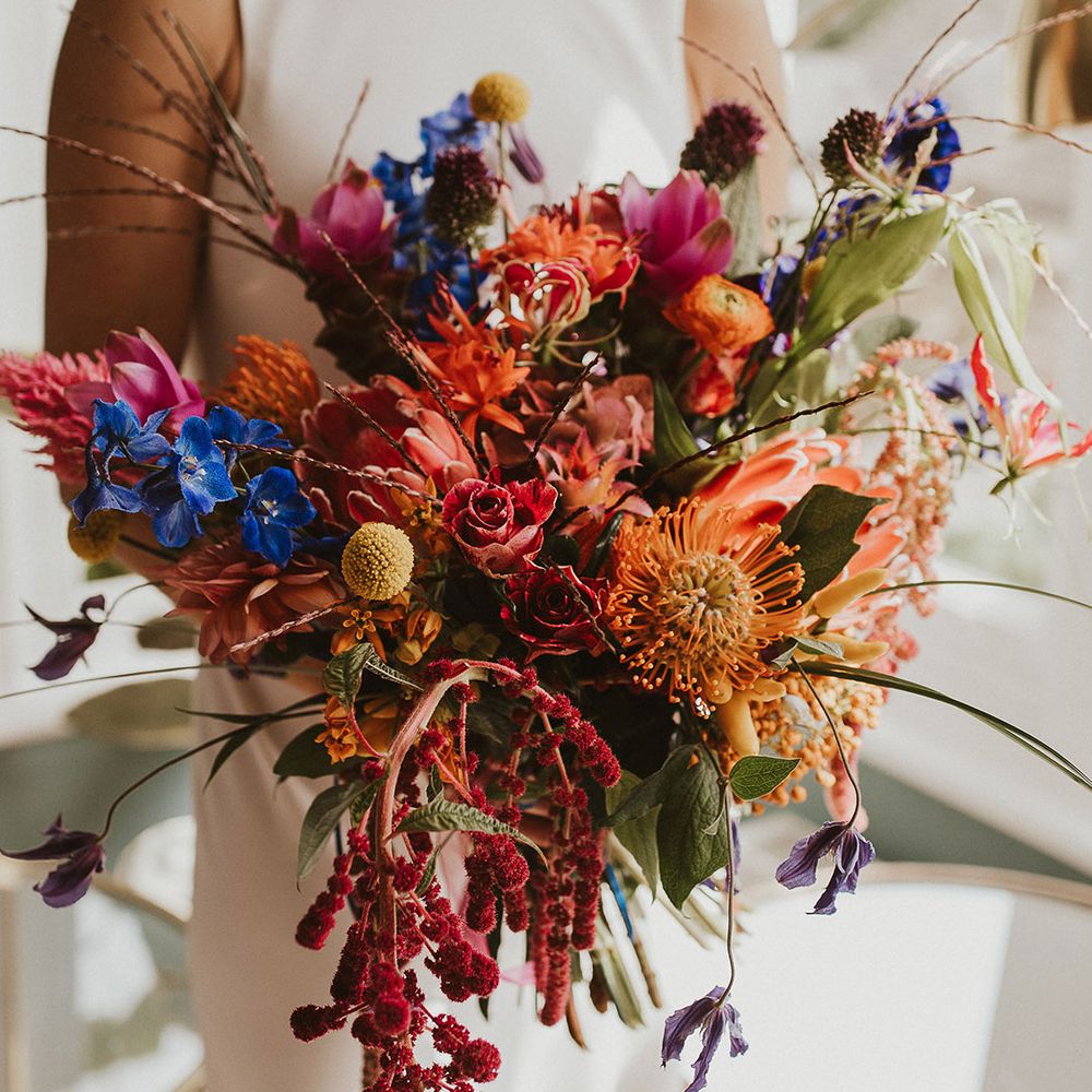 colourful wedding bouquet with billy bobs, ranunculus, roses and foliage 