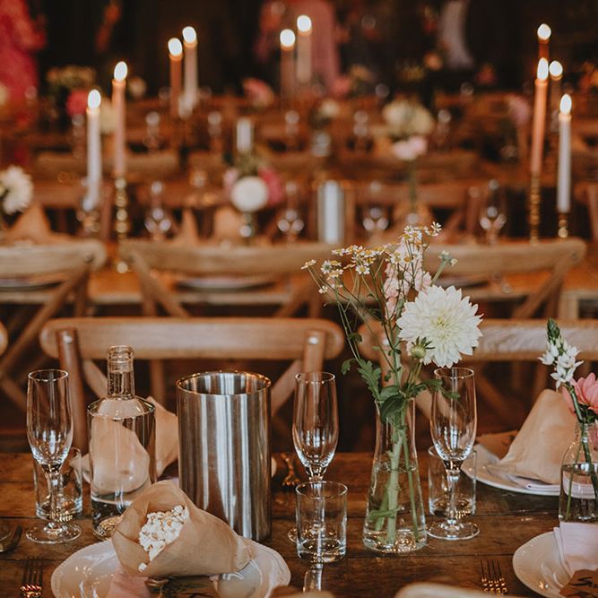 Small floral arrangements line wooden banquet tables complete with avocado dyed fabric napkins 