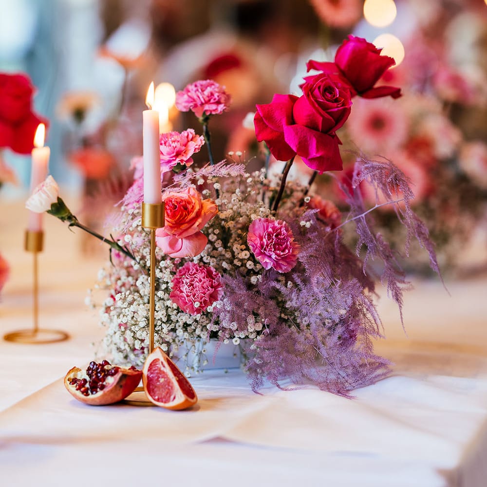 Bright pink floral centrepiece and dried fruit decor for modern tablescape 