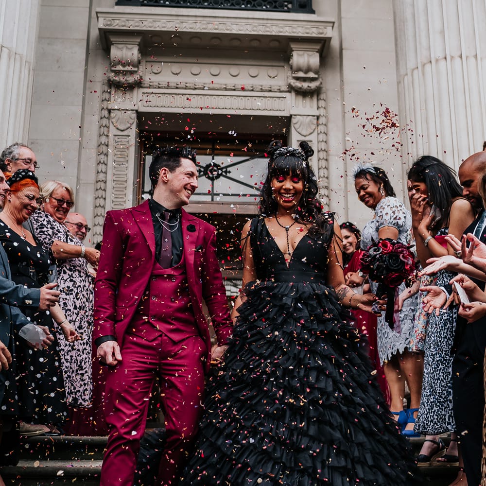 Bride & groom leave wedding ceremony as they walk through colourful confetti 