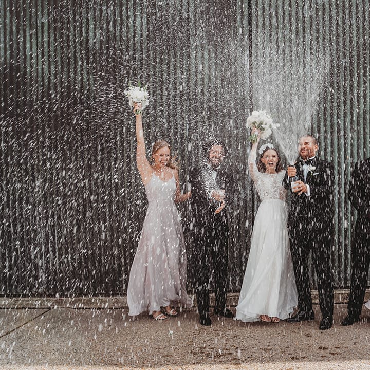 An epic champagne spray photo of the wedding party