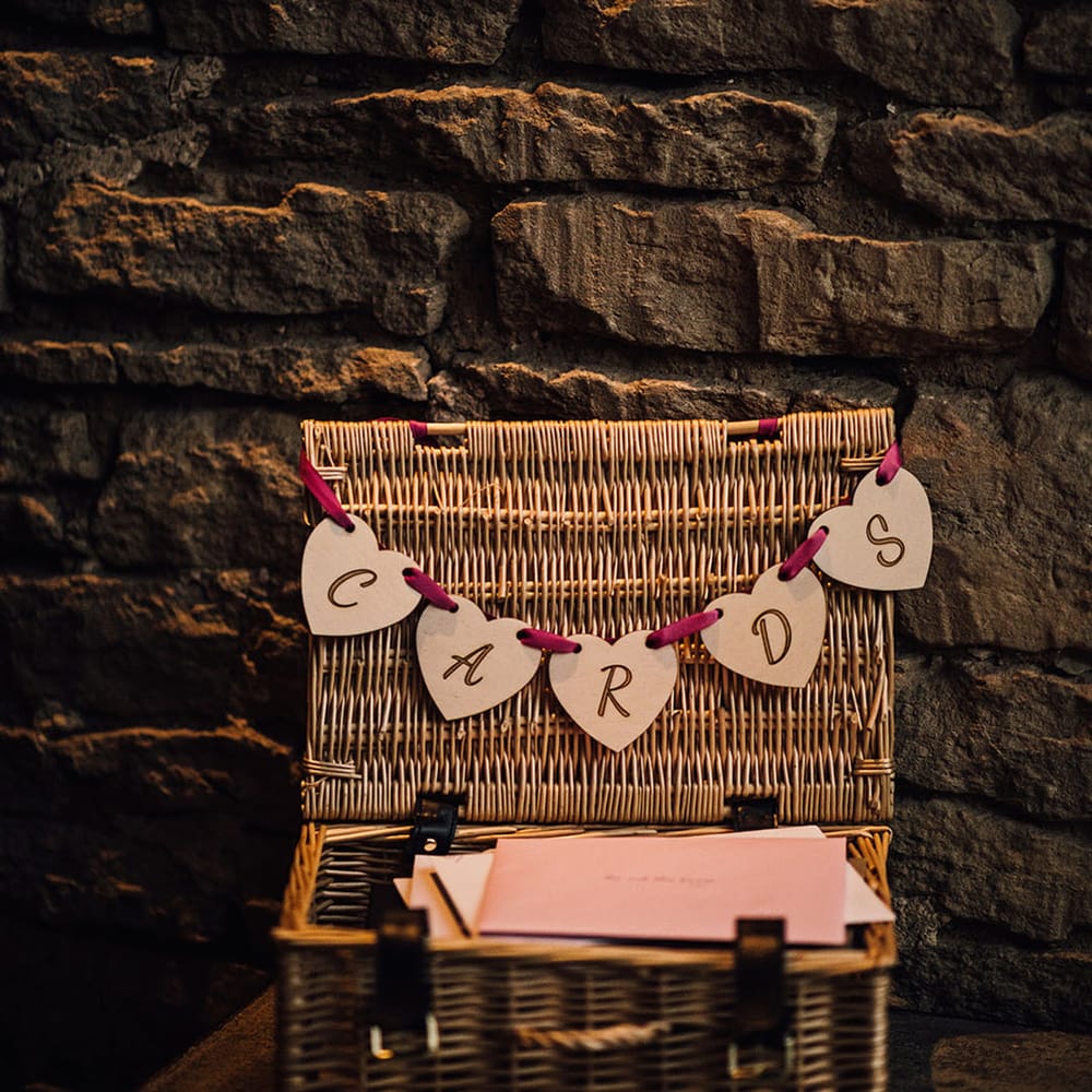 A wicker box with bunting lays on a table for the wedding cards 
