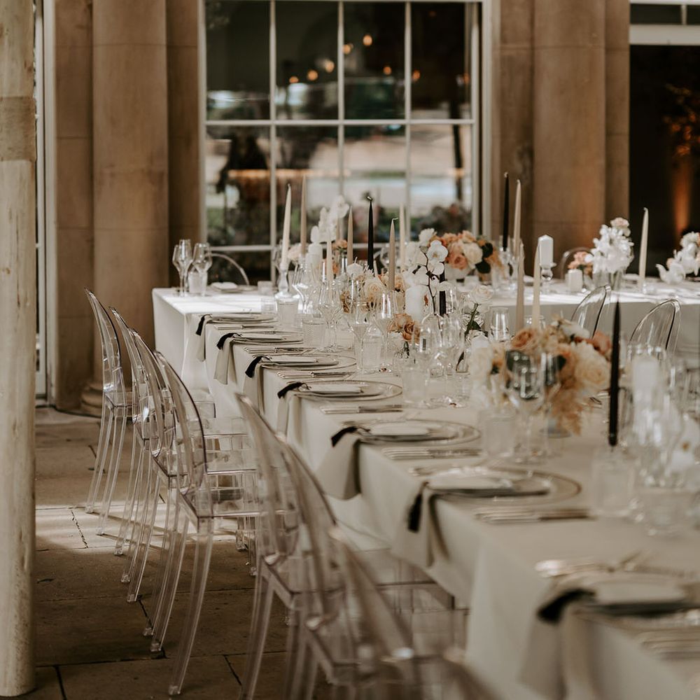 Neutral, pale pink, and black wedding tablescape with taper candles, roses, and orchids decorating the tables